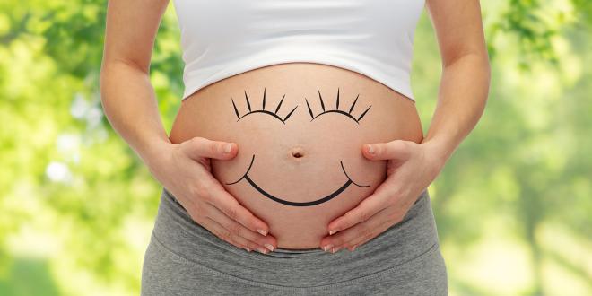 a pregnant woman with a smiley face drawn on her bump